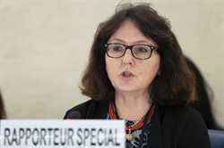 [ai] A woman with dark hair and glasses speaking at a conference, with a sign that reads 'RAPPORTEUR SPECIAL' in front of her.